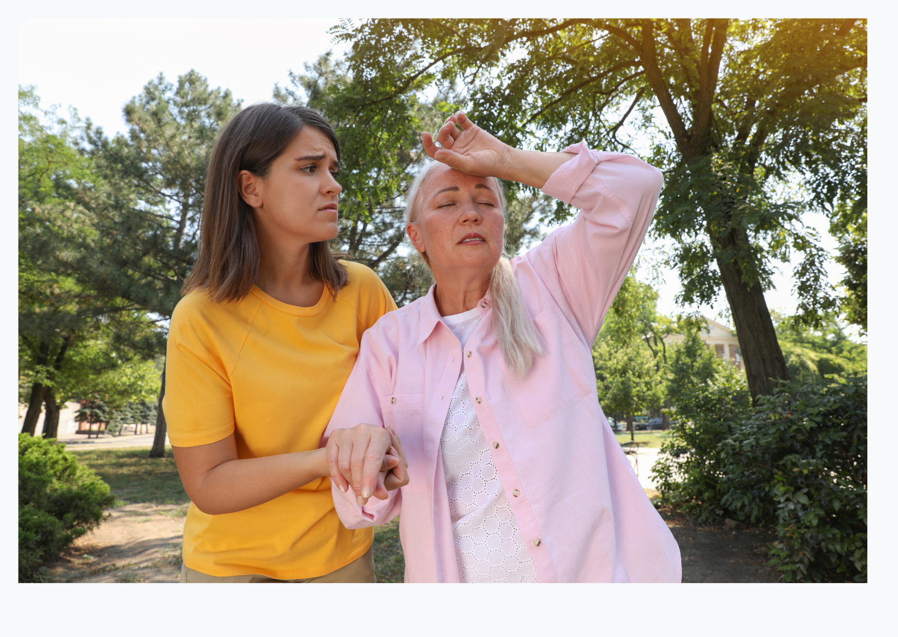 A woman is supporting and older lady suffering in the heat